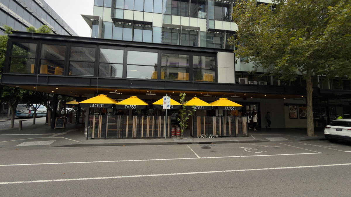 Yellow and black TAP831 branded umbrellas outside a hospitality venue